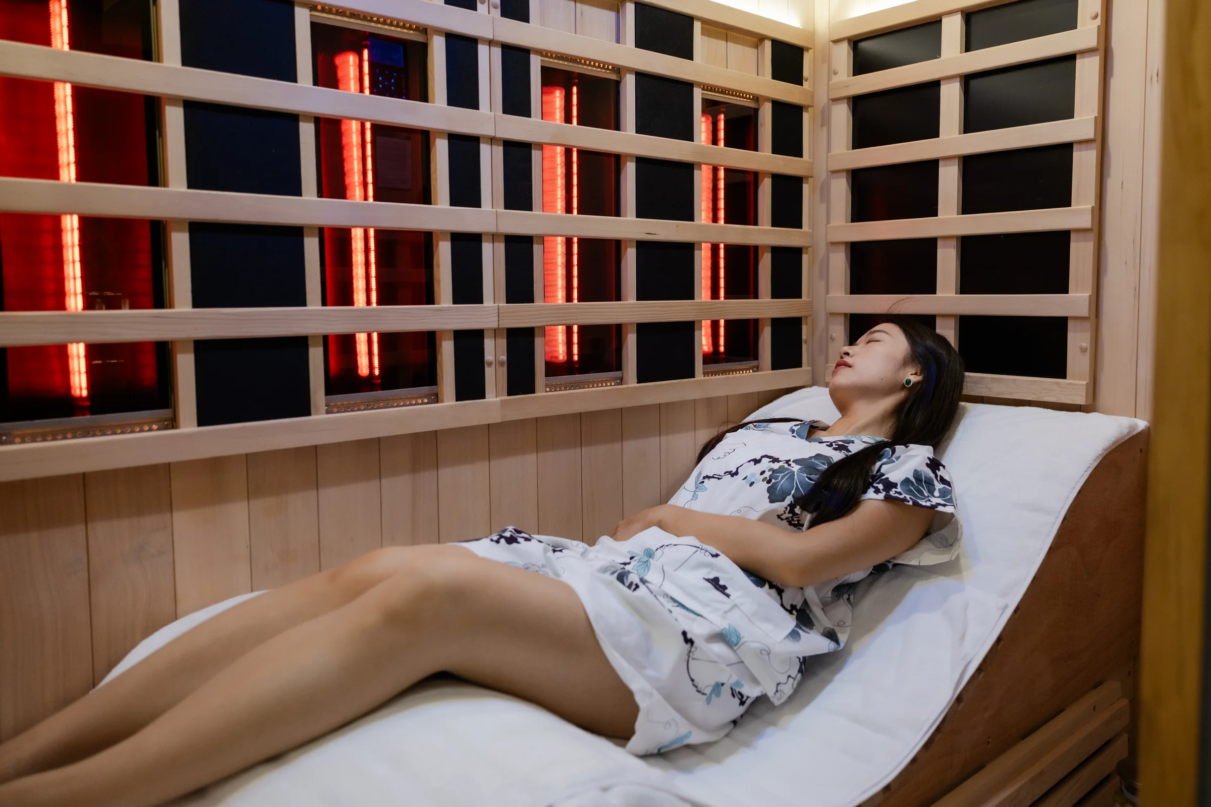 Guest lying fully reclined in a private full-spectrum infrared sauna suite at O2 Light Bar Singapore
